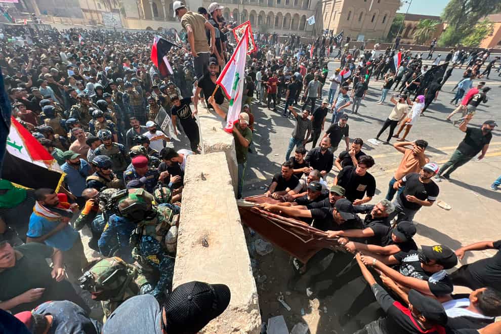 Protesters try to remove concrete barriers and cross the bridge towards the Green Zone area in Baghdad (Ali Abdul Hassan/AP)