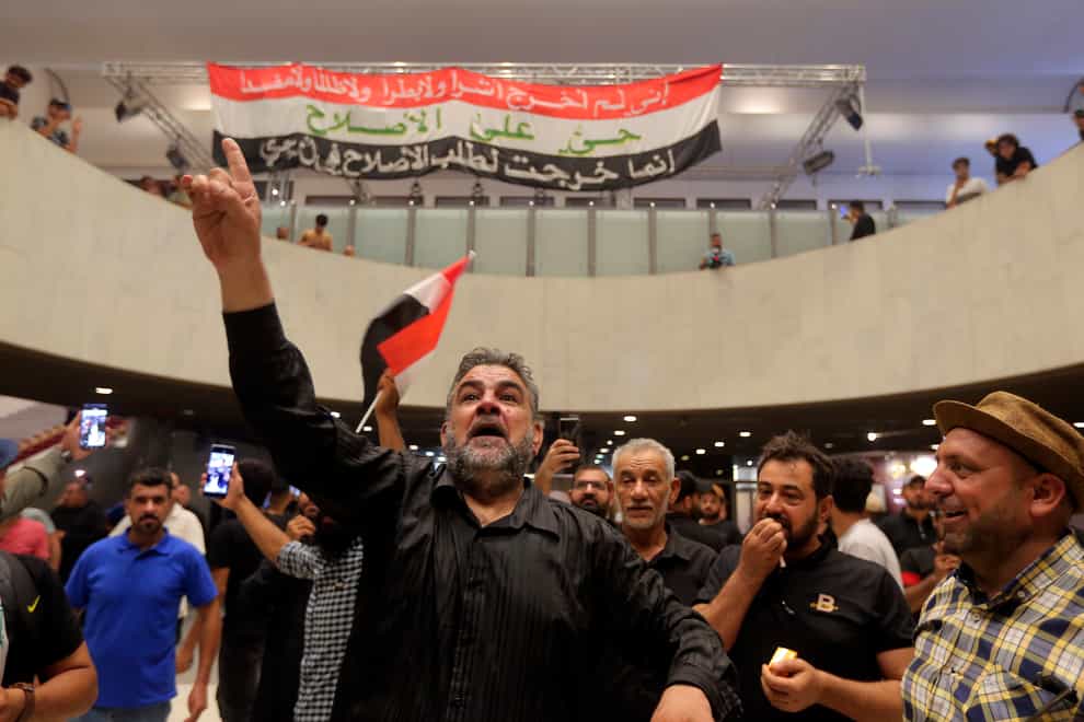 Iraqi protesters pose with national flags inside the parliament building in Baghdad, Iraq, Sunday, July 31, 2022. Thousands of followers of an influential Shiite cleric stormed into Iraq’s parliament on Saturday, for the second time in a week, protesting government formation efforts led by his rivals, an alliance of Iran-backed groups. (AP Photo/Anmar Khalil)