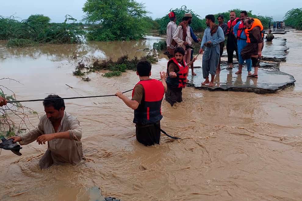 Rescue workers help villagers to evacuate them from flooded area caused by heavy rains, in Lasbella, a district in Pakistan’s Baluchistan province (AP)