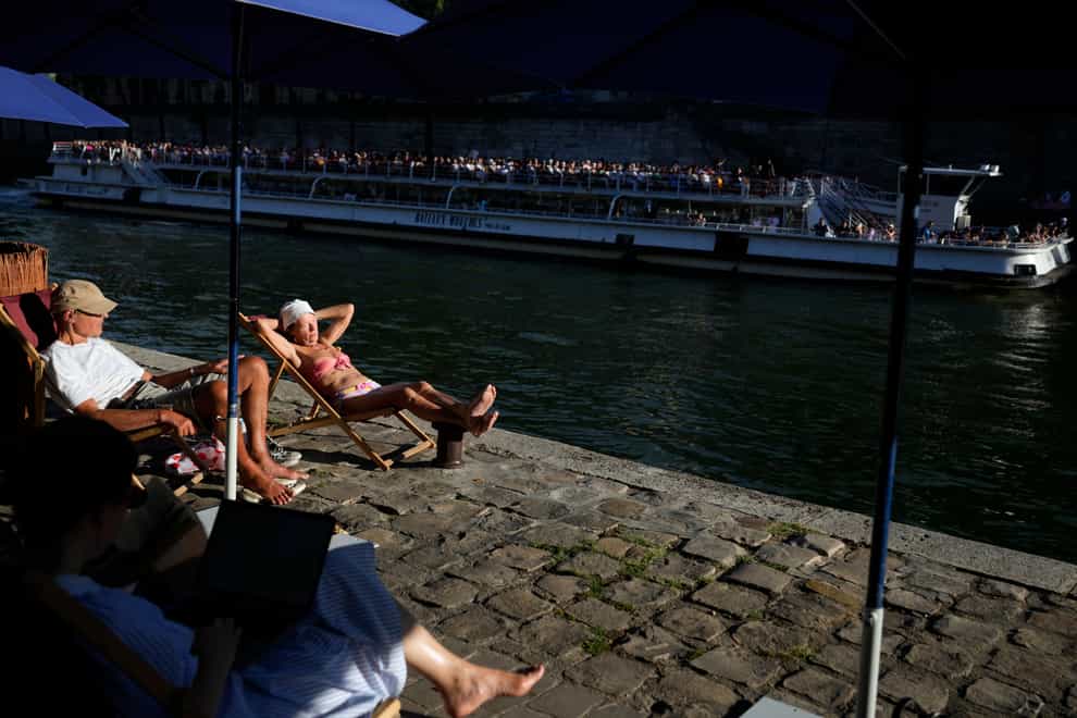 Parisians and tourists take sunbathe along the Seine River amid hot weather in Paris, France (Francois Mori/AP)