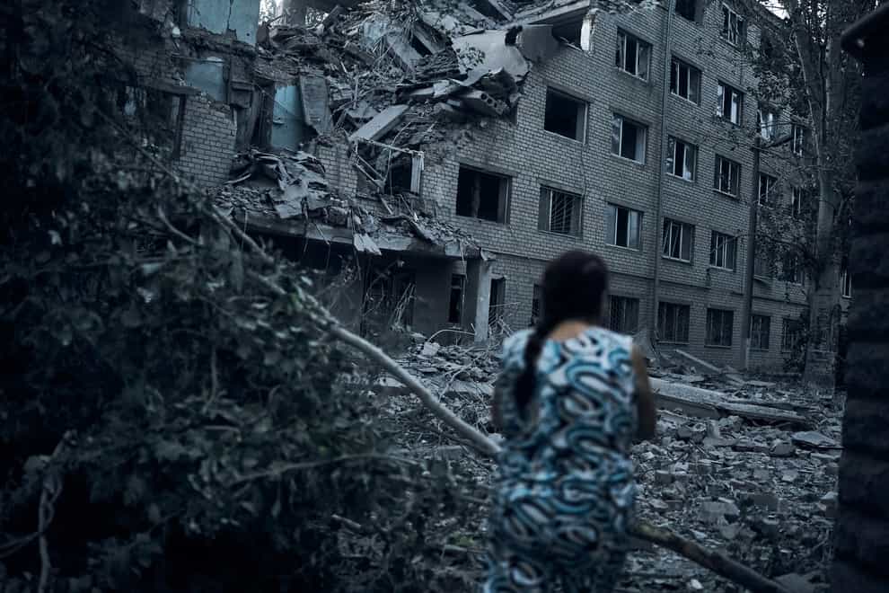 A Ukrainian woman walks amid the debris of a residential building following night shelling in Mykolaiv, Ukraine, Tuesday, Aug. 2, 2022. (AP Photo/Kostiantyn Liberov)
