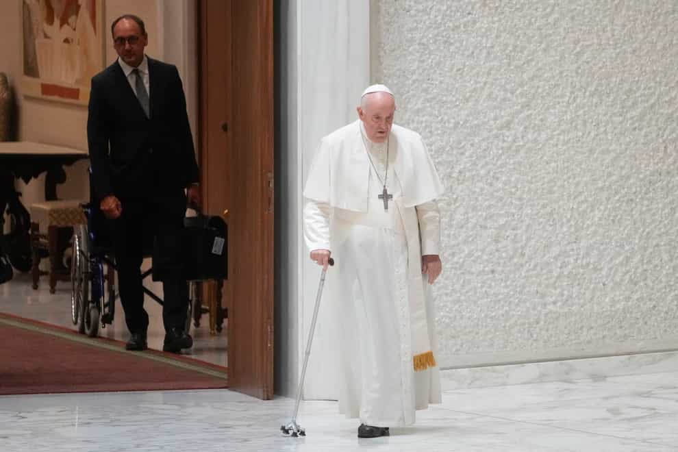 Massimiliano Strappetti, left, watches Pope Francis walking in thew Paul VI hall on the occasion of the weekly general audience at the Vatican, Wednesday, Aug. 3, 2022. Francis has promoted the Vatican nurse whom he credited with saving his life to be his “personal health care assistant.” The Vatican announced the appointment of Massimiliano Strappetti, currently the nursing coordinator of the Vatican’s health department, in a one-line statement Thursday.(AP Photo/Gregorio Borgia)