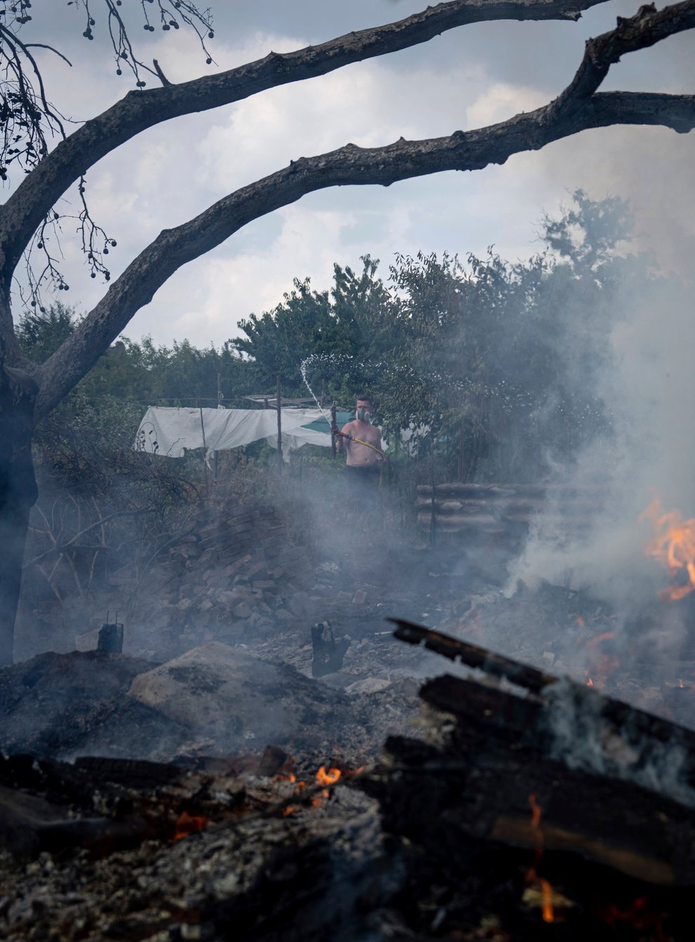 A local resident tries to stop a fire at a neighbour’s house destroyed by a Russian attack in Mykolaiv, Ukraine (Evgeniy Maloletka/AP)