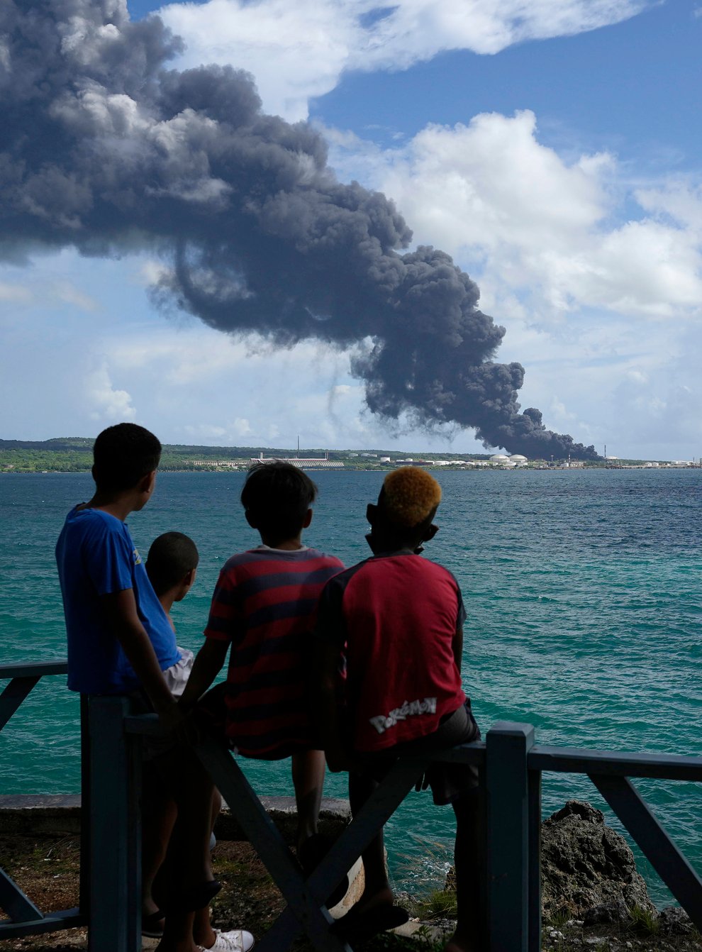 People watch a huge plume of smoke caused by a blaze after lightning struck an oil storage tank in Cuba (Ramon Espinosa/AP)