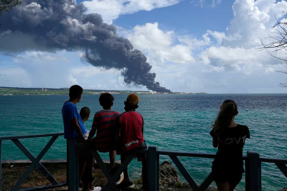 People watch a huge plume of smoke caused by a blaze after lightning struck an oil storage tank in Cuba (Ramon Espinosa/AP)
