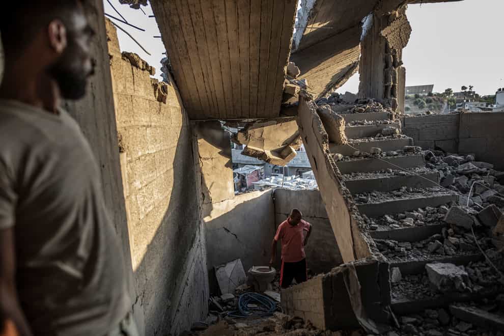 Palestinians inspect their house after it was hit by an Israeli airs trike in Gaza (Fatima Shbair/AP)