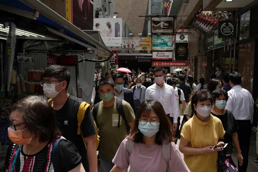 People wearing face masks walk along a side street in Mongkok, a shopping district of Hong Kong, Monday, Aug. 8, 2022. Hong Kong will reduce the mandatory hotel quarantine for overseas arrivals to three days from a week, the city’s leader said on Monday (Kin Cheung/AP/PA)