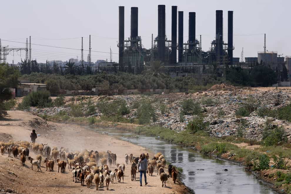 Shepherds walk with their sheep in front of the power plant at Nusseirat refugee camp, central Gaza Strip, Monday, Aug. 8, 2022. Israel on Monday said it was partially reopening crossings into Gaza for humanitarian needs and would fully open them if calm was maintained. Fuel trucks were seen entering a cargo crossing for the first time since crossings with the strip were closed last week, prompting a fuel shortage that ground Gaza’s sole power plant to a halt on Saturday. (AP Photo/Adel Hana)