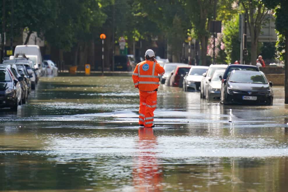 A Thames Water official stands in flood water on Hornsey Road, Holloway, north London, after a 36in water main burst, causing flooding (Jonathan Brady/PA)