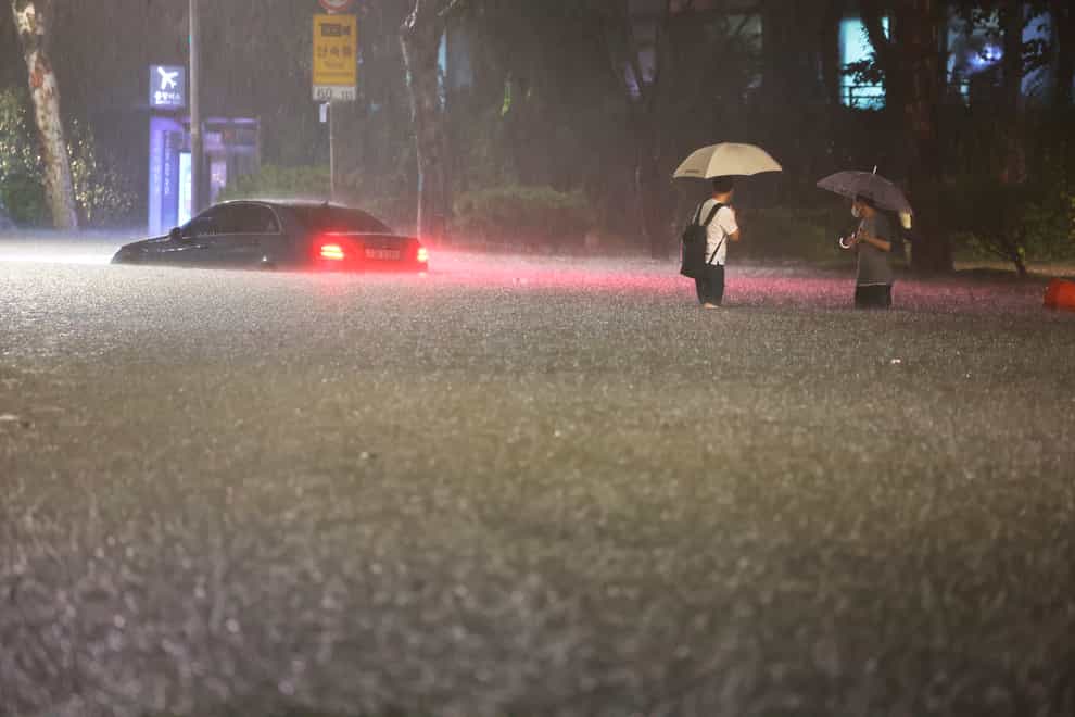 A vehicle is submerged on a flooded road in (Hwang Kwang-mo/Yonhap via AP)