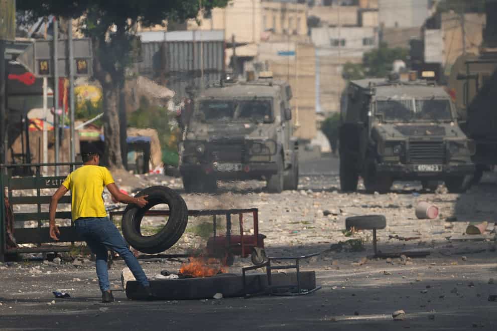 A Palestinian demonstrator burns tyres during clashes with the Israeli army while forces carry out an operation in the West Bank town of Nablus (Majdi Mohammed/AP)
