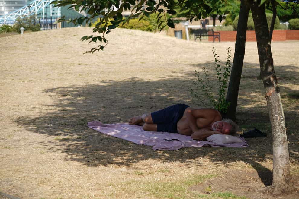A man lying in the shade of a tree (Yui Mok/PA)