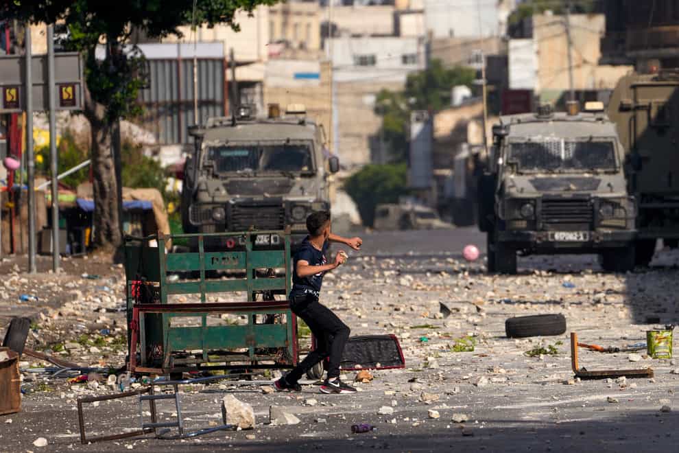 Palestinian demonstrators clash with the Israeli army while forces carry out an operation in the West Bank town of Nablus (Majdi Mohammed/AP)