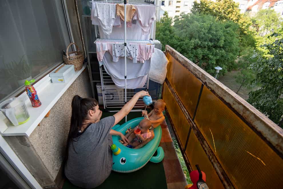 Krisztina plays with her children on their balcony in Budapest, Hungary (Anna Szilagyi/AP)