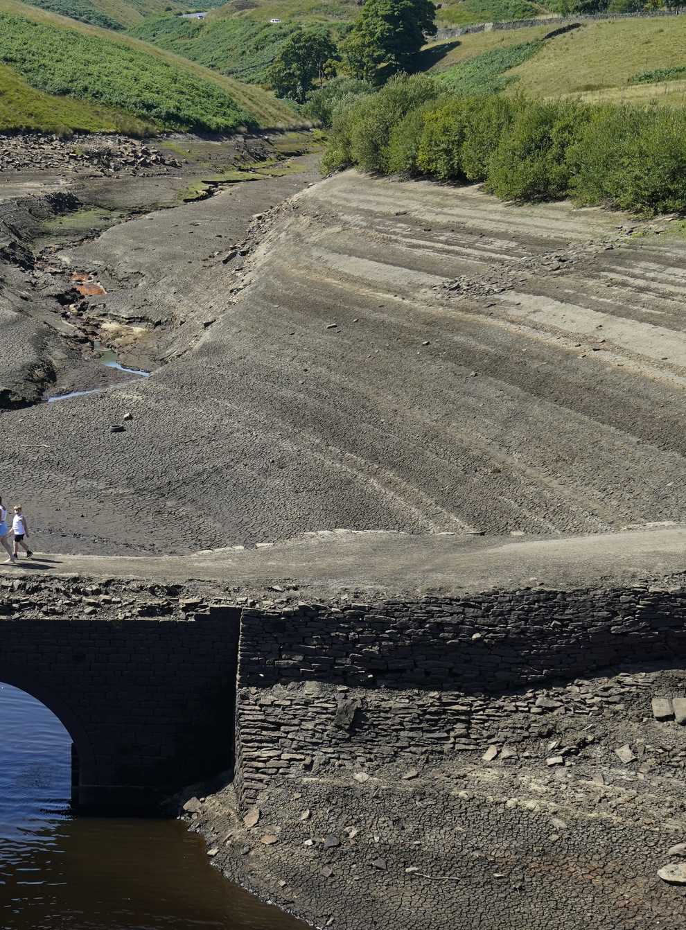 People walk across a previously submerged bridge at Baitings reservoir in Ripponden, West Yorkshire (Danny Lawson/PA)