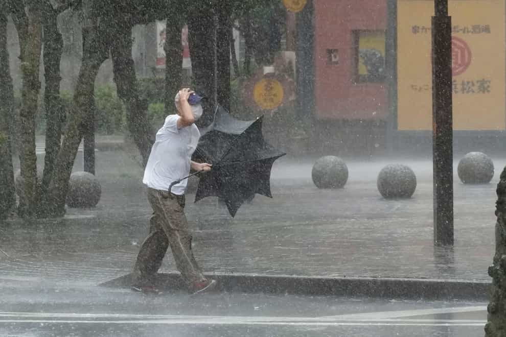 A man is drenched by the rain brought by Tropical Storm Meari (Kyodo News via AP)