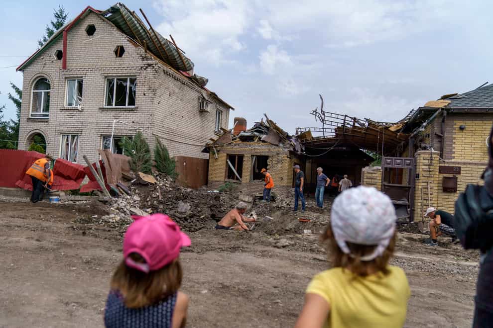 Children watch as workers clean up after a rocket strike on a house in Kramatorsk, Donetsk region (David Goldman/AP)