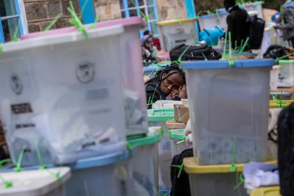 A weary electoral worker rests her head on ballot boxes (Ben Curtis/PA)