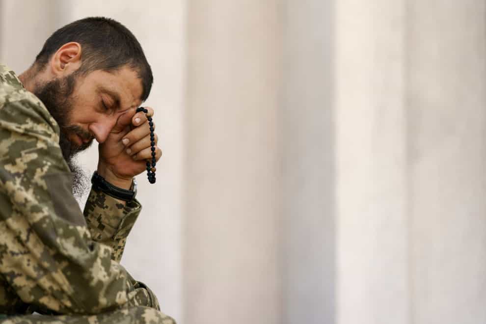 A Ukrainian serviceman prays during a church service (David Goldman/AP)