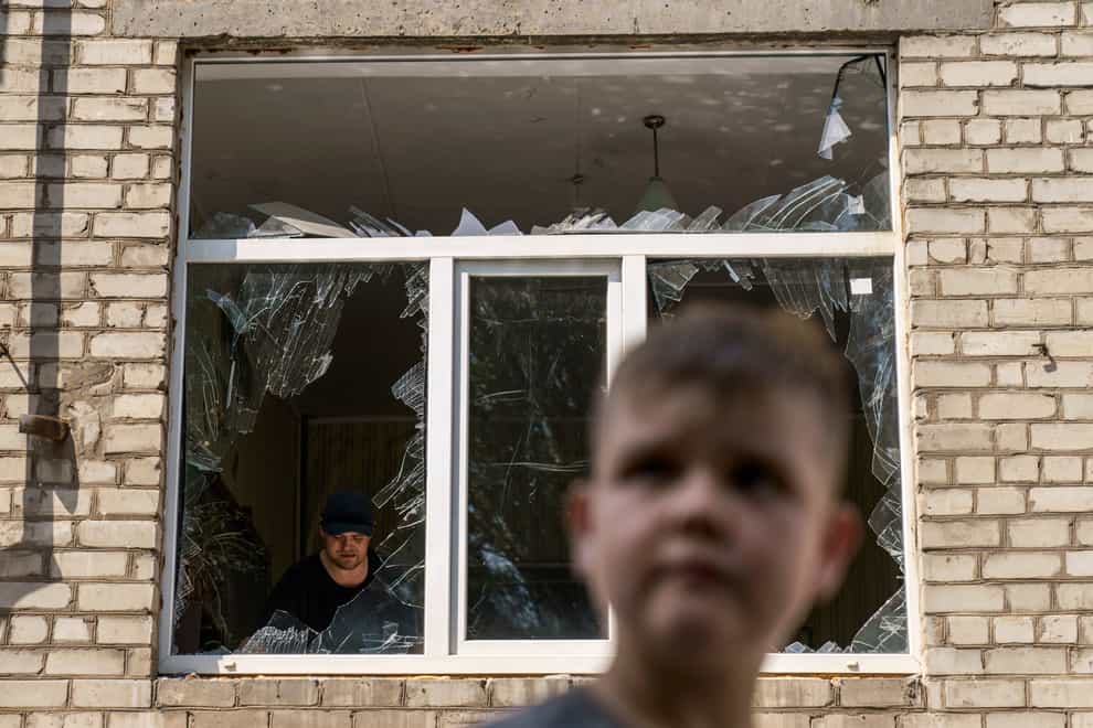 A worker cleans up inside as a boy passes the Kramatorsk College of Technologies and Design (David Goldman/AP)