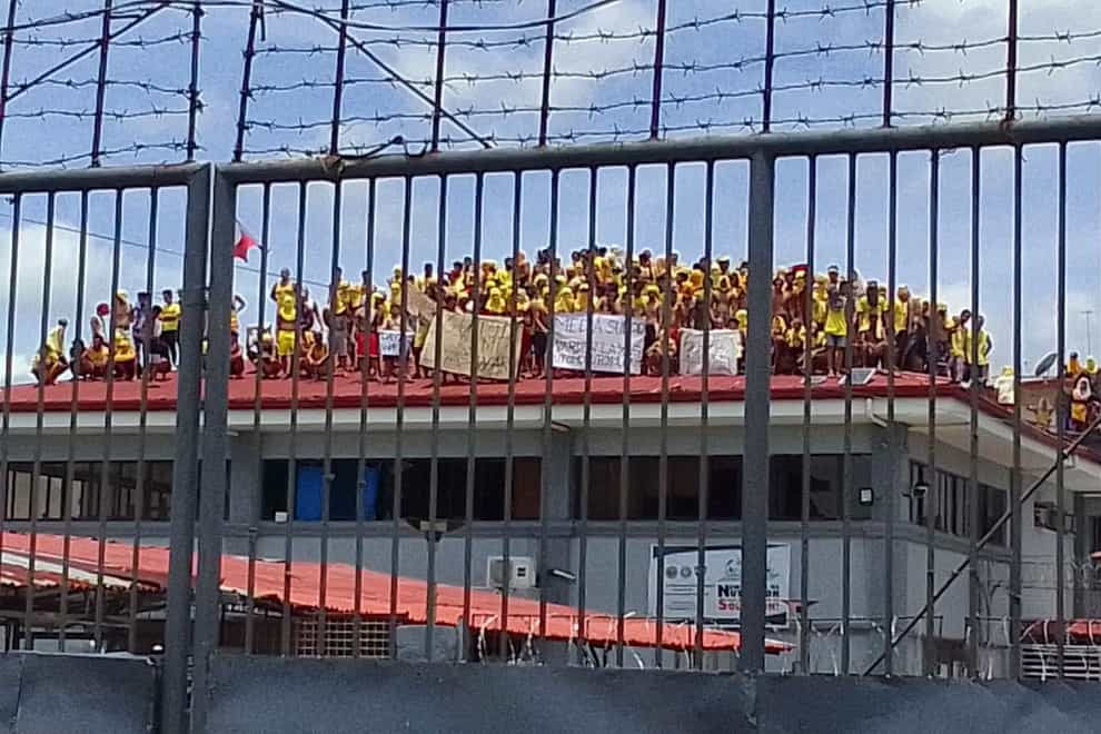 Filipino inmates stand on top of the roof of a prison building as they protest in Pototan town, Iloilo province, central Philippines (Fred Pasgala/AP)