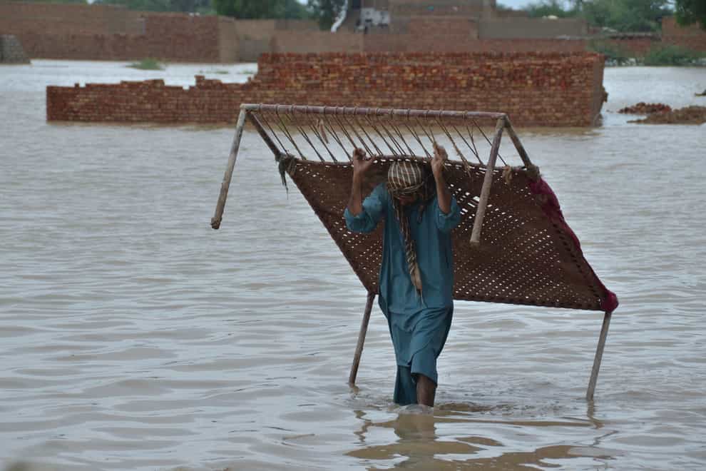 A man carries a cot after he salvaged it from his flood-hit home in Jaffarabad, a district of Pakistan’s south-western Baluchistan province (Zahid Hussain/AP)