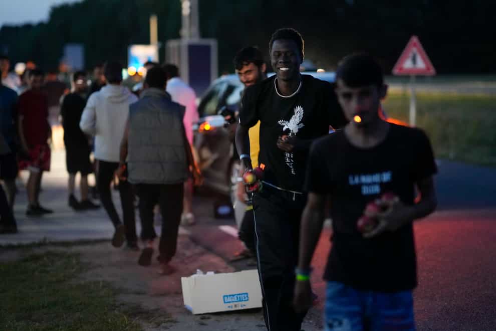Refugees run off with goods distributed by a passer-by as hundreds of migrants prepared to spend the night outside an overcrowded asylum seekers centre in Ter Apel, northern Netherlands (Peter Dejong/AP)