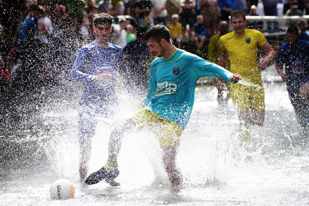 Footballers from Bourton Rovers create a splash as they fight for the ball during the annual River Windrush football match (Ben Birchall/PA)