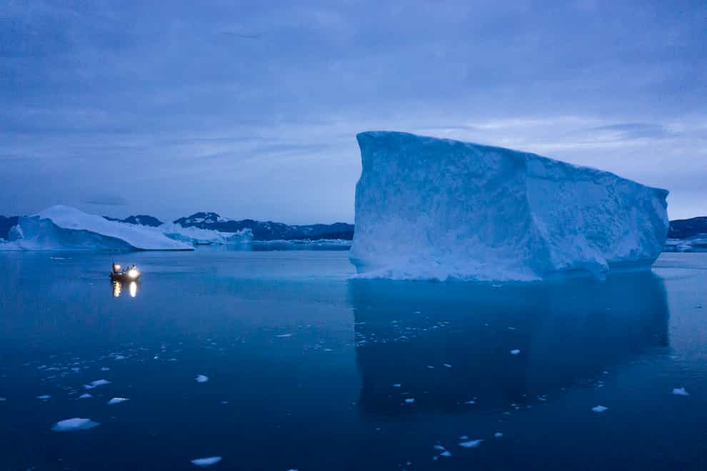 A boat navigates at night next to large icebergs in eastern Greenland in 2019 (Felipe Dana/AP)