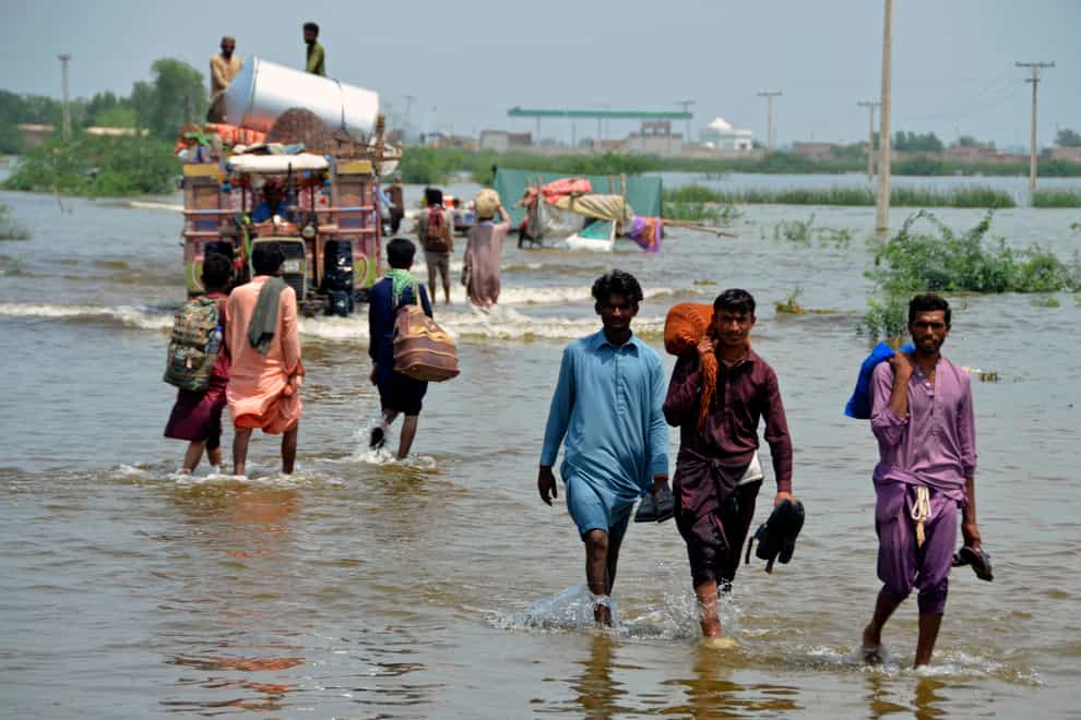 People wade through a flooded area of Sohbatpur, a district of Pakistan’s south-western Baluchistan province (Zahid Hussain/AP)