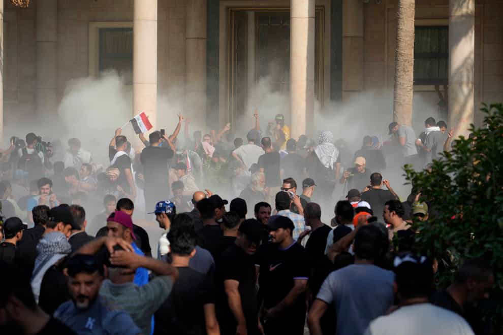 Iraqi security forces fire tear gas on the followers of Shiite cleric Muqtada al-Sadr inside the government palace grounds, in Baghdad, Iraq (Hadi Mizban/AP)