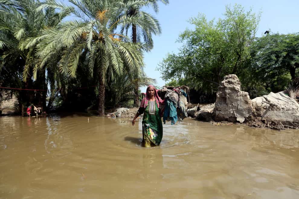 A woman wades through a flooded area after heavy rains in the Shikarpur district of Sindh province, Pakistan (Fareed Khan/AP)