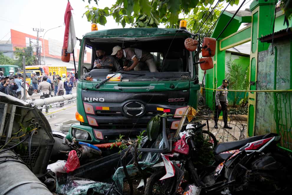 Police officers try to move a truck after a traffic accident in Bekasi (AP)
