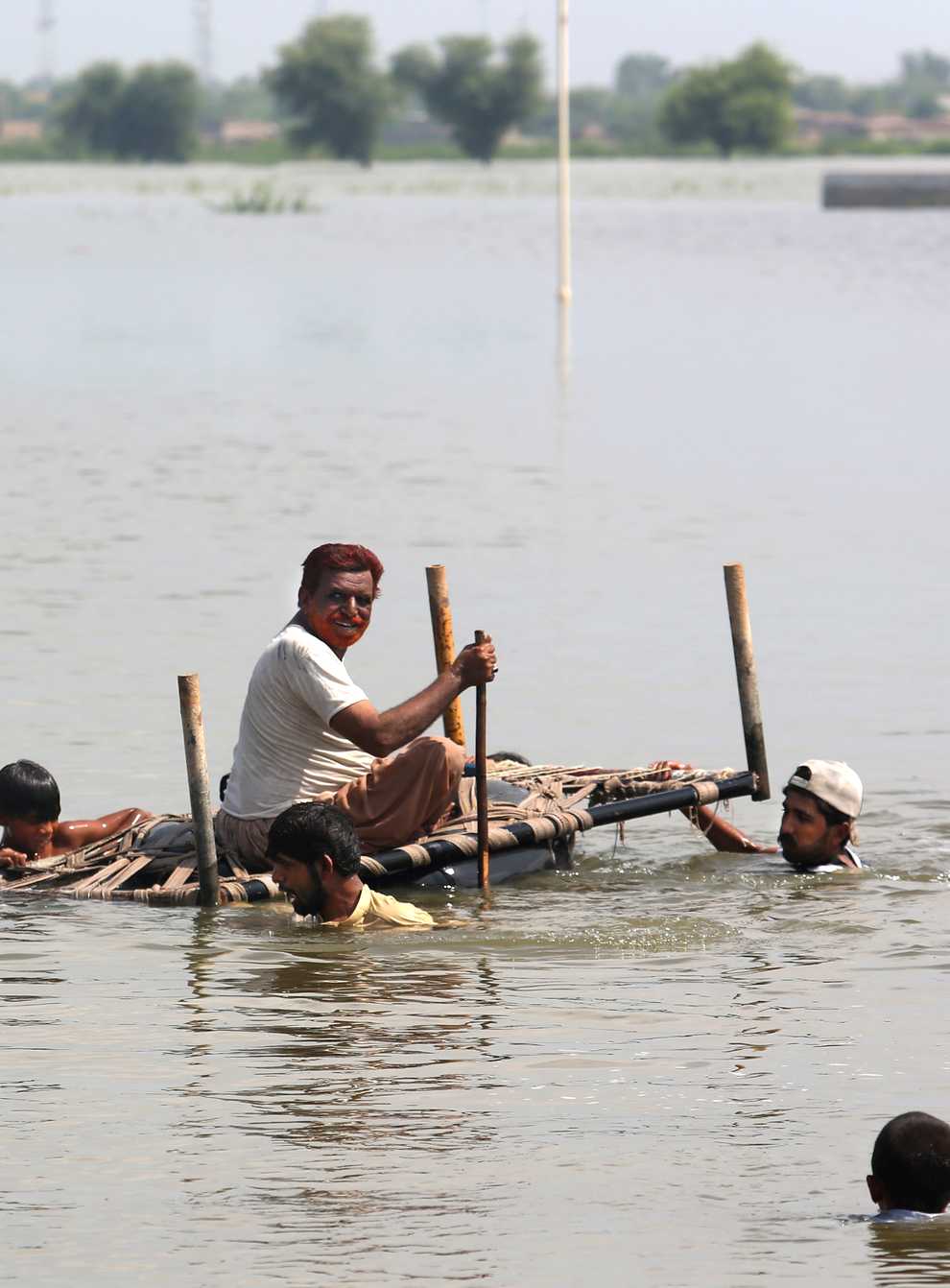 People try to salvage belongings from their nearby flooded home caused by heavy rain in Pakistan (Fareed Khan/AP)