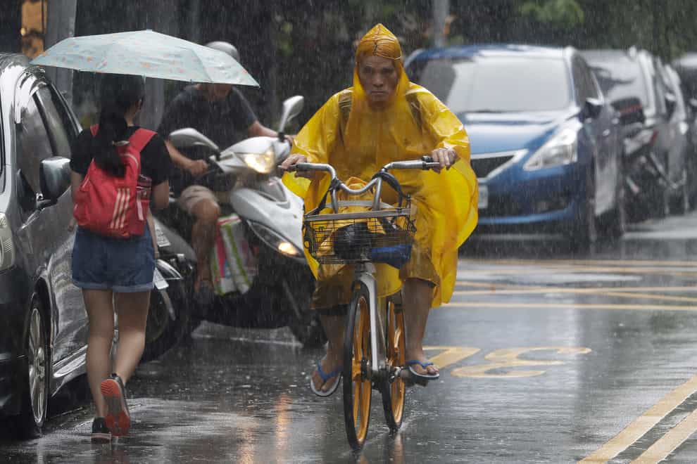People make their way through heavy rain ahead of the approaching Typhoon Hinnamnor in Taipei, Taiwan (Chiang Ying-ying/AP)