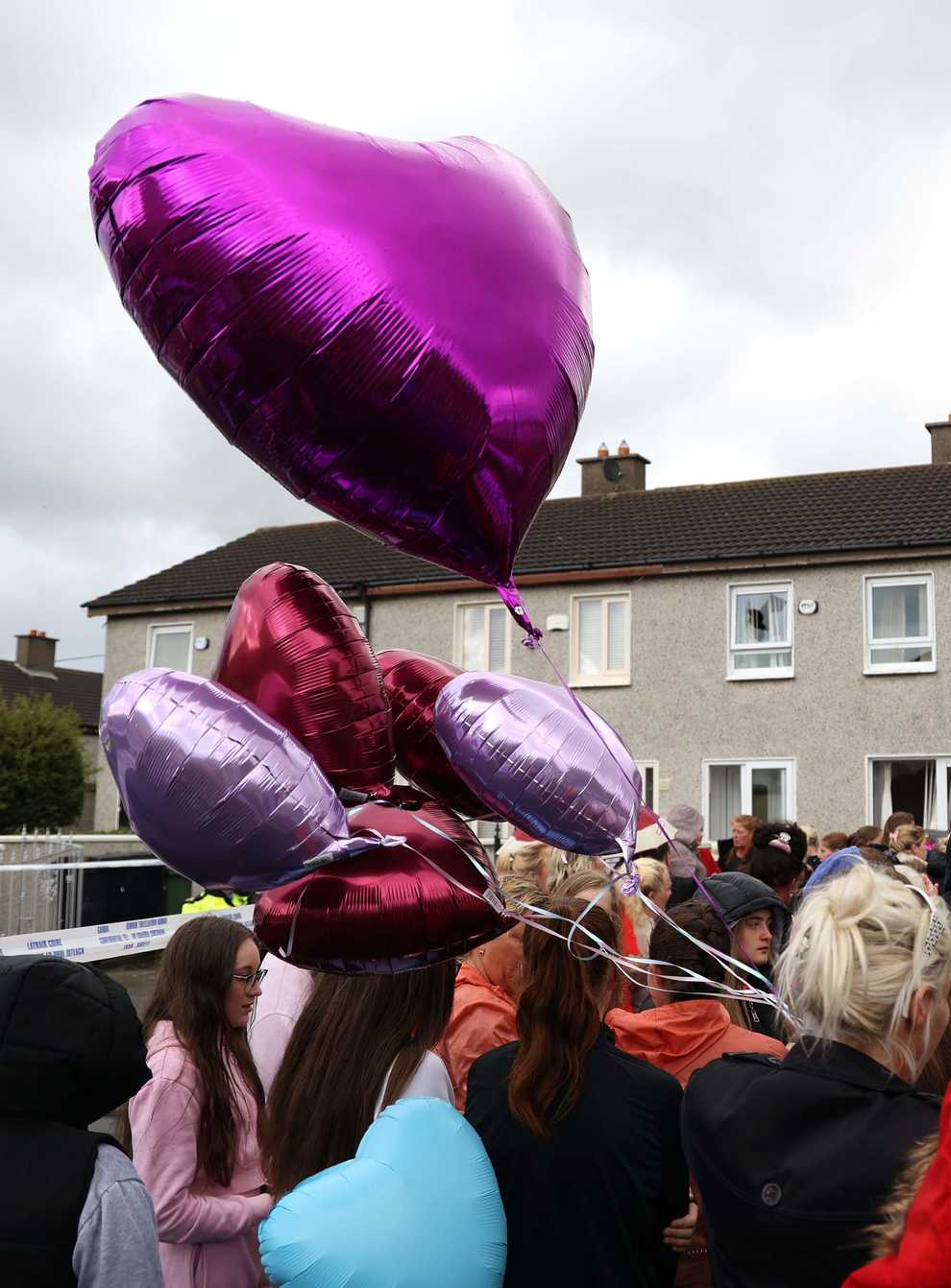 People attend a vigil outside a house on Rossfield Avenue in Tallaght, Dublin, where Lisa Cash, 18, and her eight-year-old twin siblings Christy and Chelsea Cawley died in a violent incident. Picture date: Monday September 5, 2022.
