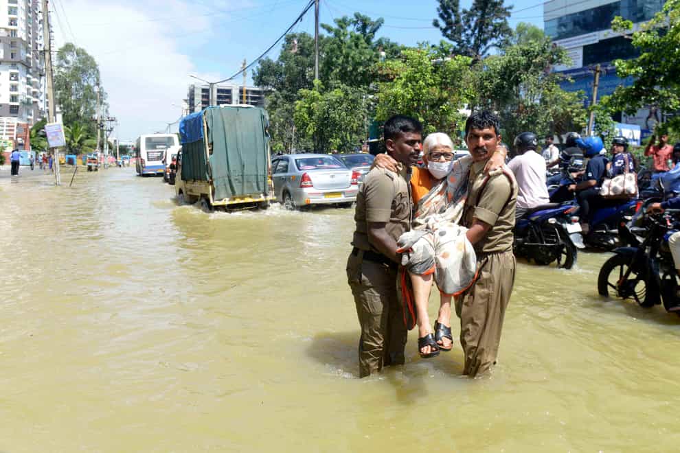 Firefighters help an elderly woman to safety (Kashif Masood/AP)