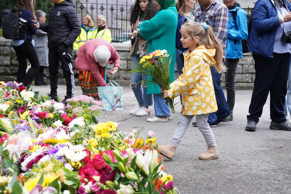 A young girl leaves flowers at the gate of Balmoral (Owen Humphreys/PA)
