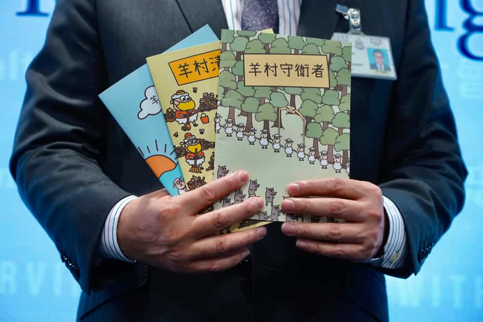 Li Kwai-wah, senior superintendent of the Police National Security Department, with three children’s books that revolve around a village of sheep which has to deal with wolves from a different village in Hong Kong (Vincent Yu/AP)