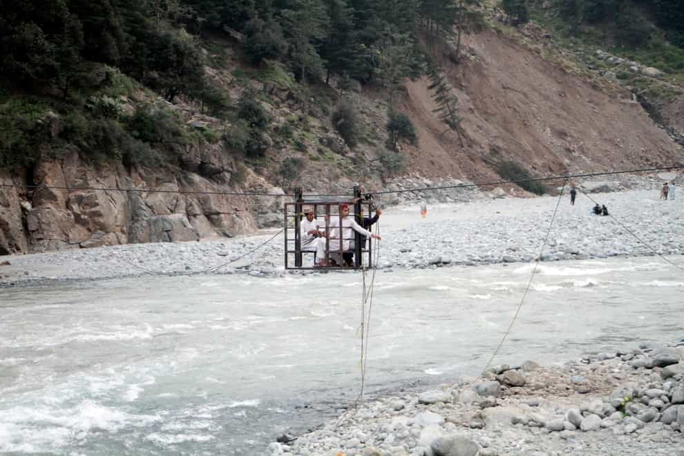 People cross a river on a suspended cradle in Kalam Valley in northern Pakistan (Naveed Ali/AP)