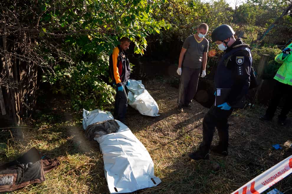 Ukrainian police work during the exhumation of unidentified bodies of people killed by the Russian troops in the village of Grakovo, freed by the Ukrainian army two days ago in the Kharkiv region (AP)