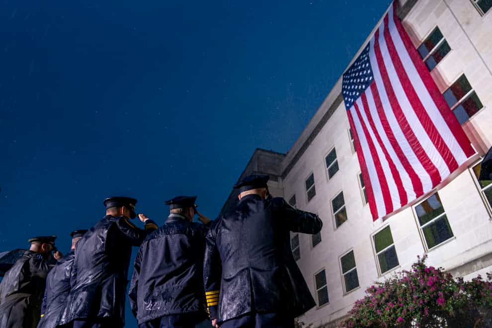First responders salute in a driving rain as a US flag is unfurled at the Pentagon in Washington (Andrew Harnik/AP)