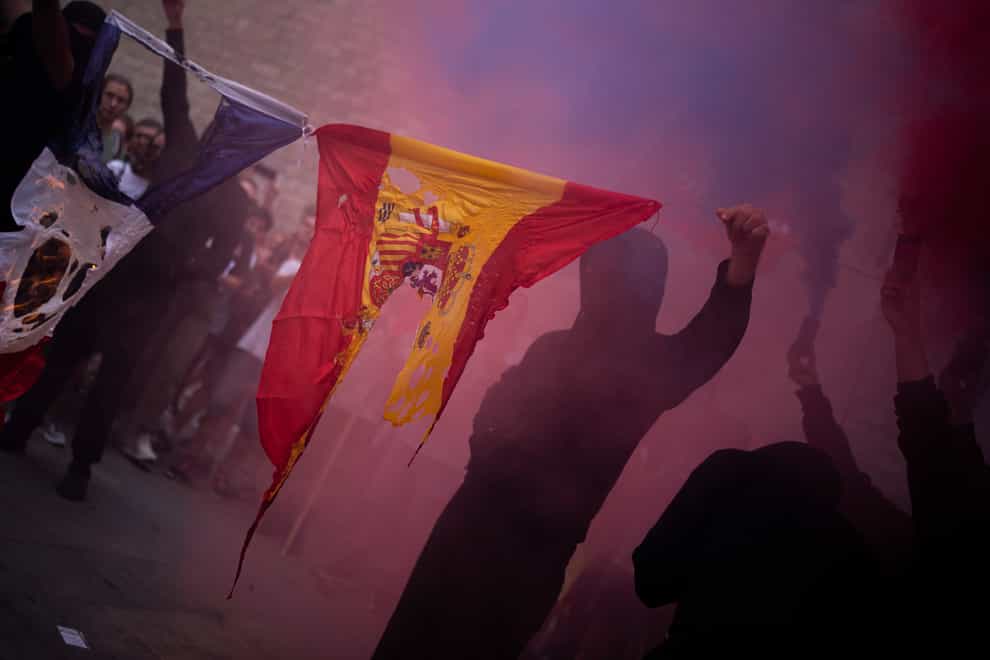 Protesters burn Spain and France flags as they take part in a demonstration during the Catalan National Day in Barcelona, Spain (Joan Mateu Parra/AP)