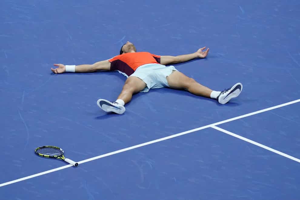 Carlos Alcaraz lies on the court after winning the US Open (Mary Altaffer/AP)
