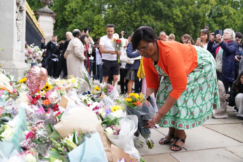 A woman lays flowers in remembrance of the Queen outside Buckingham Palace (Kirsty O’Connor/PA)
