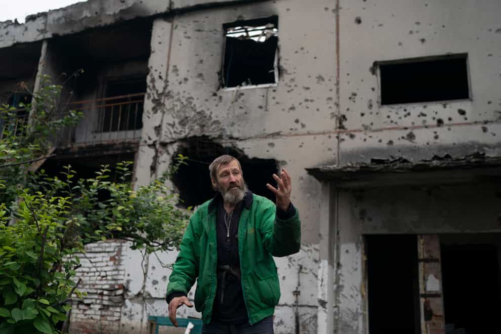 Viacheslav Myronenko, 71, stands in front of the entrance of a damaged building where he lives in the freed village of Hrakove, Ukraine (Leo Correa/AP)