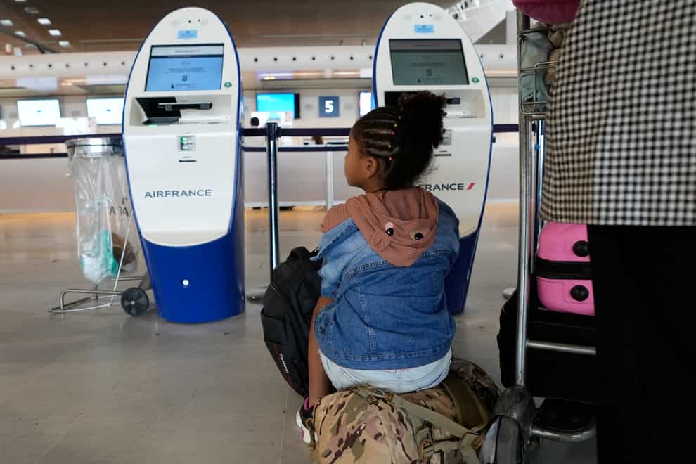 Travellers wait by empty check-in desks at Roissy Charles de Gaulle airport, north of Paris (Francois Mori/AP)