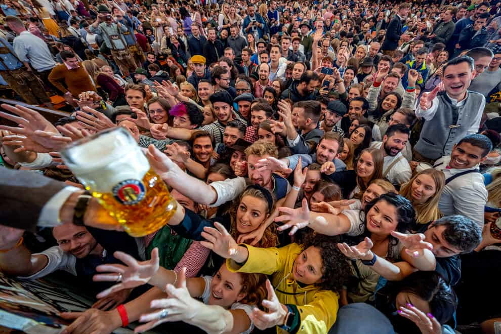 Young people reach out for free beer in one of the beer tents on the opening day of the 187th Oktoberfest festival in Munich, Germany (AP)