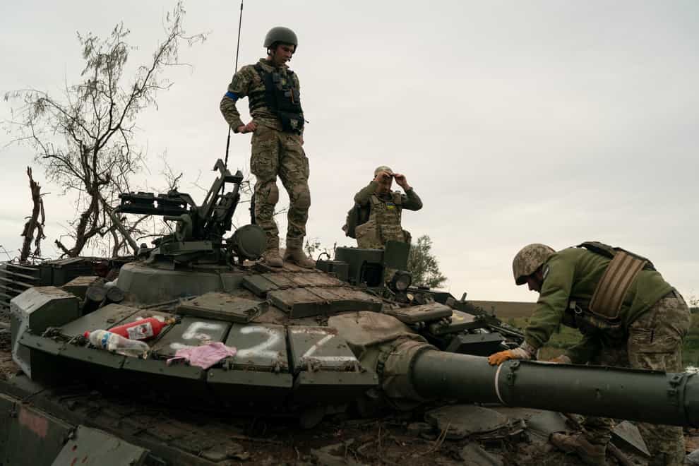 Ukrainian servicemen stand atop a destroyed Russian tank in a retaken area near the border with Russia in Kharkiv region (Leo Correa/AP)