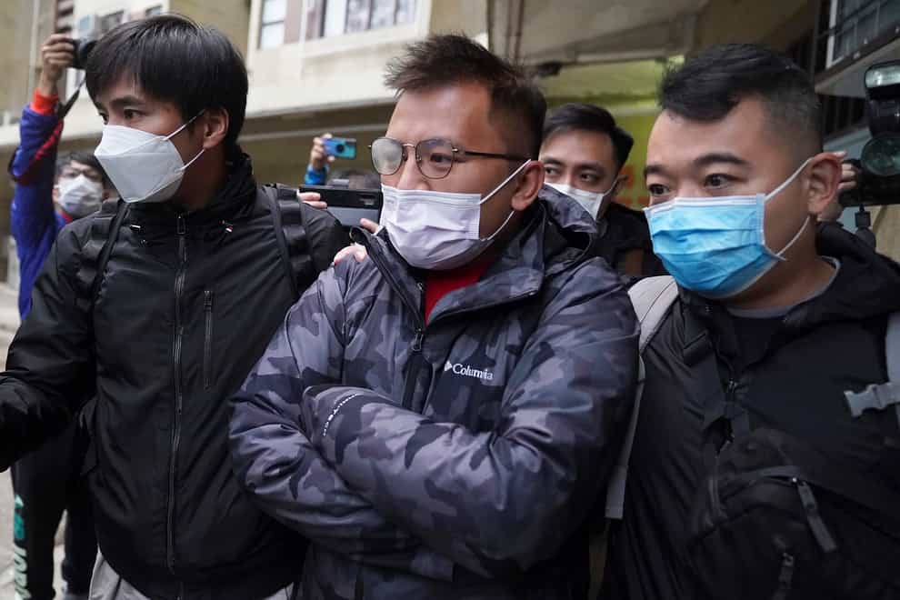 Senior editor of Stand News, Ronson Chan, centre, is arrested by police officers in Hong Kong (AP)
